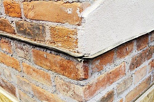 Membrane noire insérée horizontalement dans un mur de briques au-dessus du sol