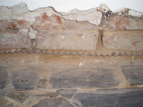 Plaques d'acier inoxydable enfoncées dans le joint d'un mur ancien comme barrière contre l'humidité