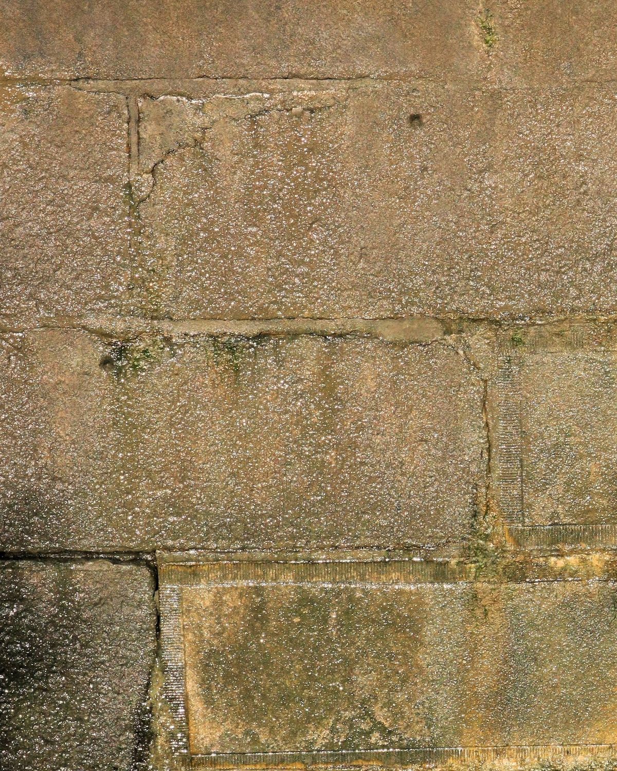 Mur en pierre taillée marqué de traînées sombres d'humidité