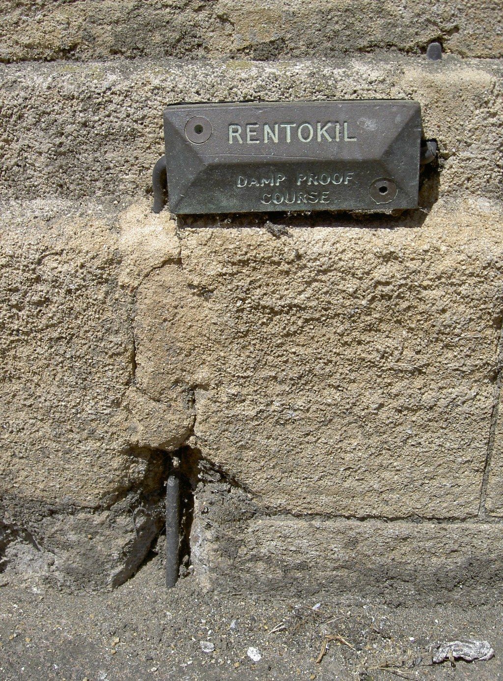 Plaque métallique d'une ancienne entreprise de traitement contre l'humidité fixée sur un mur en pierre