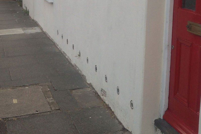 Façade enduite avec une rangée de siphons atmosphériques ronds en pied de mur